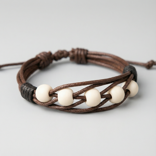 دستبند با مهرههای سفید رنگ و بند قهوهای بافتدار، قابل تنظیم و مناسب هدیه دادن.