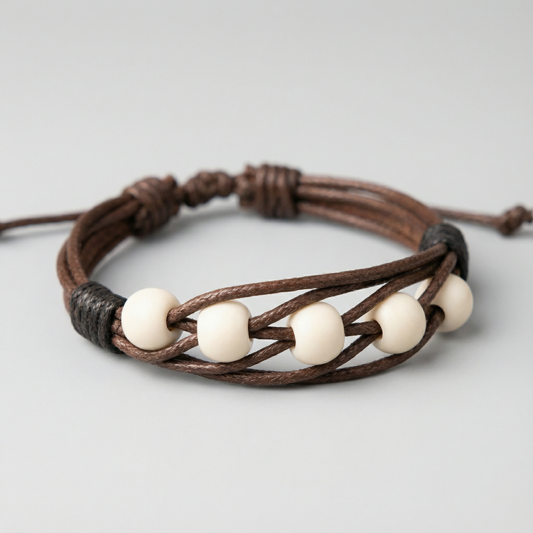 دستبند با مهرههای سفید رنگ و بند قهوهای بافتدار، قابل تنظیم و مناسب هدیه دادن.