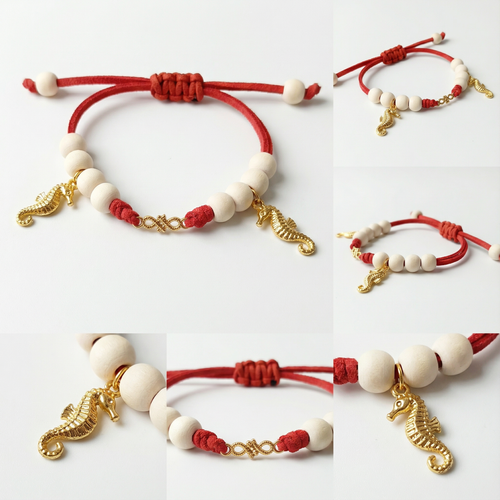 دستبند دستساز با بند قرمز، مهرههای سفید و آویزهای طلایی نماد بینهایت و اسب دریایی